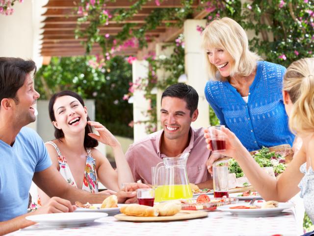 Group Of Young And Senior Couples Enjoying Family Meal