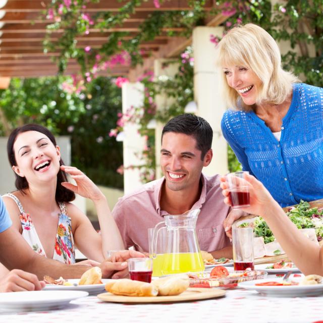 Group Of Young And Senior Couples Enjoying Family Meal